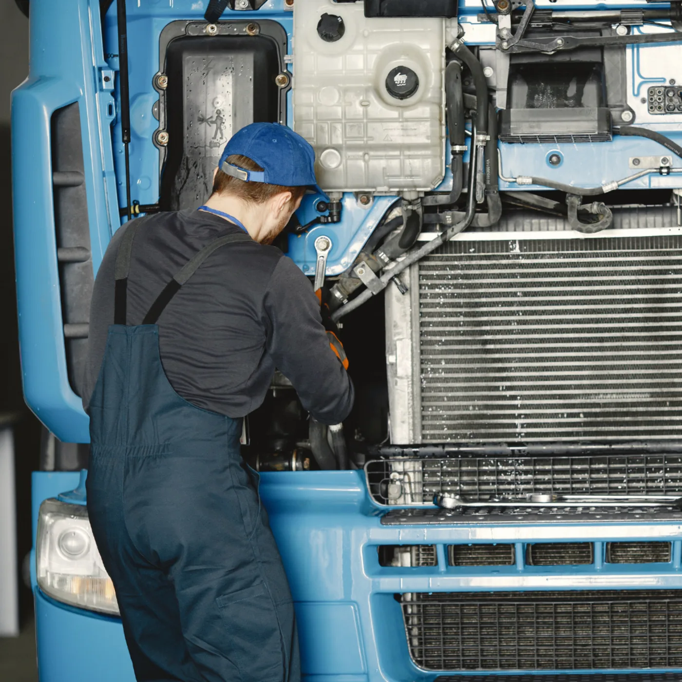 Mechaniker bei der Arbeit am geöffneten Motorraum eines großen Transporters in der Werkstatt